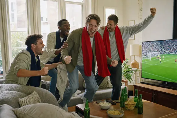 Friends celebrating a goal while watching football on IPTV at home