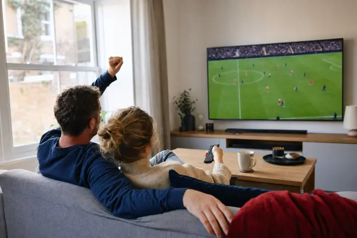 Couple watching live football on an IPTV UK subscription in a bright living room